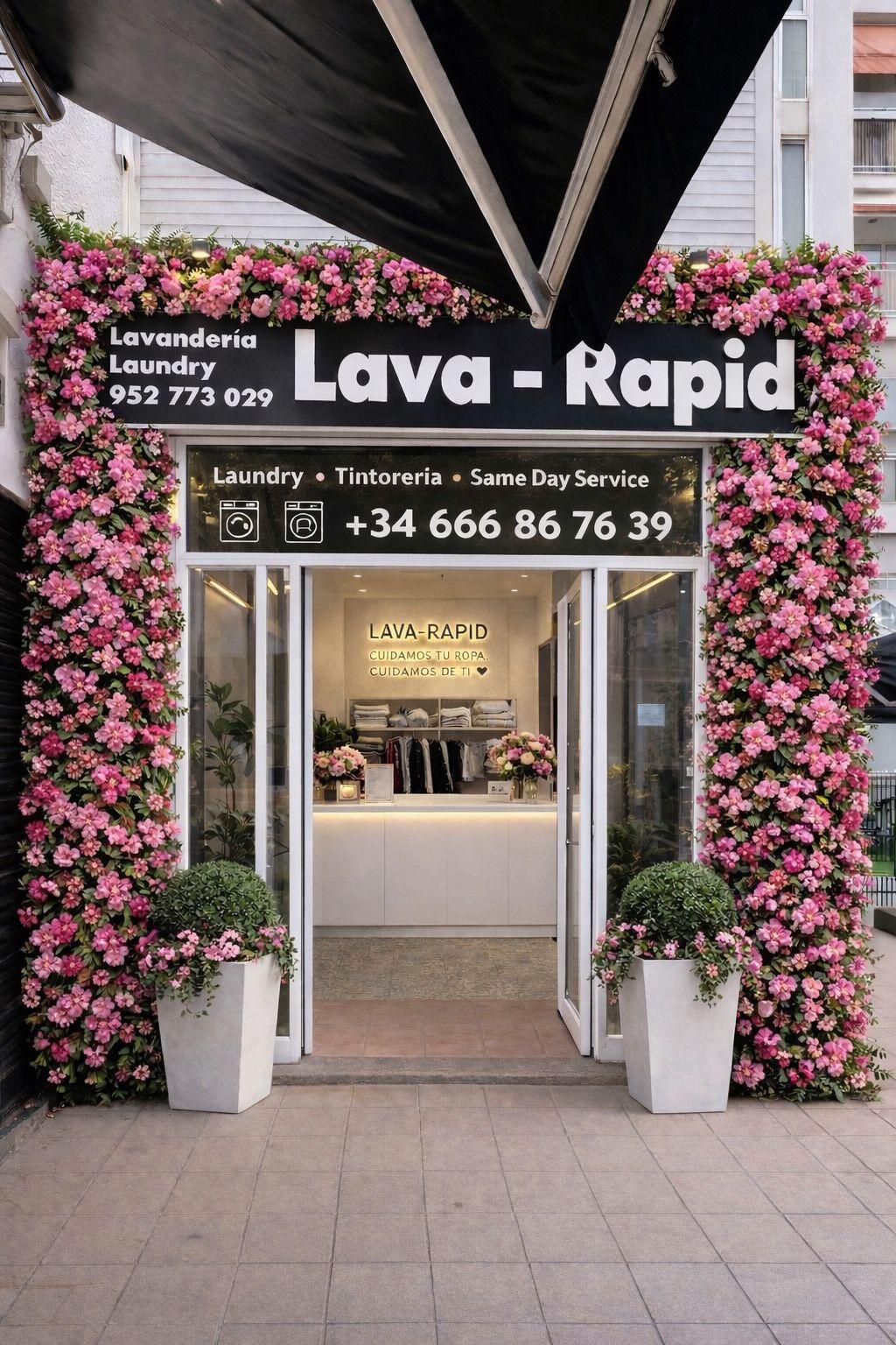 The Lava—Rapid shopfront on Calle Camilo José Cela, Marbella — black and white signage framed by pink flowers